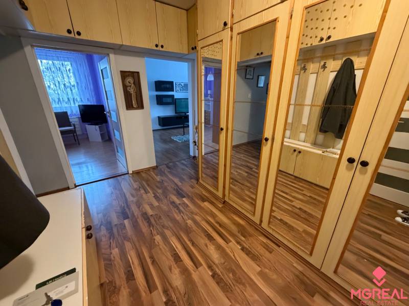 3 izbový byt bez balkóna Topoľčany  - Vstupná hala v 3-izbovom byte s podlahou s dreveným dekorom a zrkadlovými skriňami.