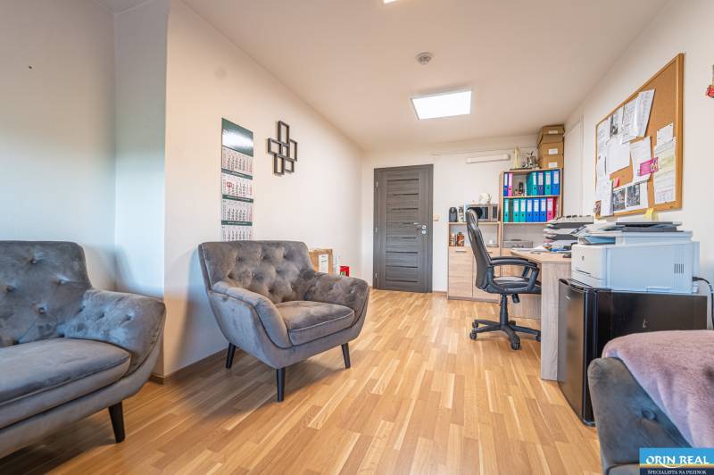 MODERNÝ KANCELÁRSKY PRIESTOR NA PRENÁJOM - Interiér kancelárie s podlahou s dreveným dekorom, pohodlnými kreslami a pracovným stolom.