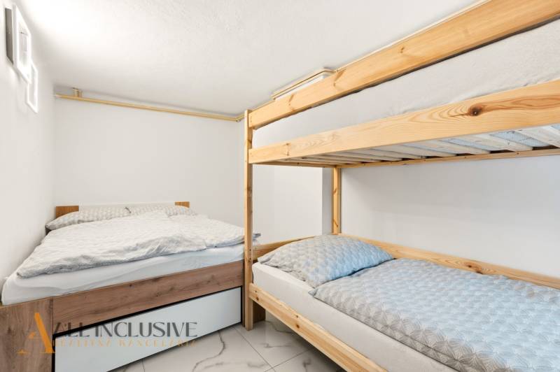 NADŠTANDARDNÁ REKREAČNÁ CHATA | DUCHONKA  - Spálňa v chate s poschodovou posteľou a ďalším lôžkom, podlahou s dreveným dekorom.