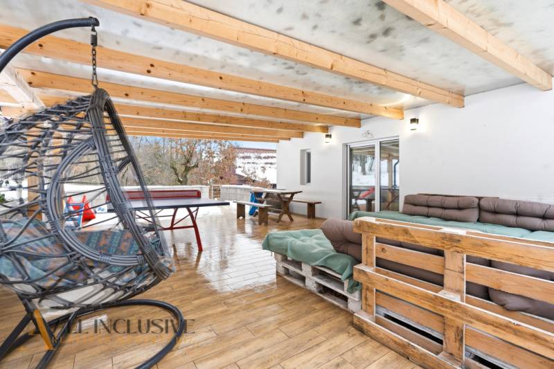 NADŠTANDARDNÁ REKREAČNÁ CHATA | DUCHONKA  - Krytá terasa chaty v Duchonke, Prašice s podlahou s dreveným dekorom, posedením a hojdačkou.