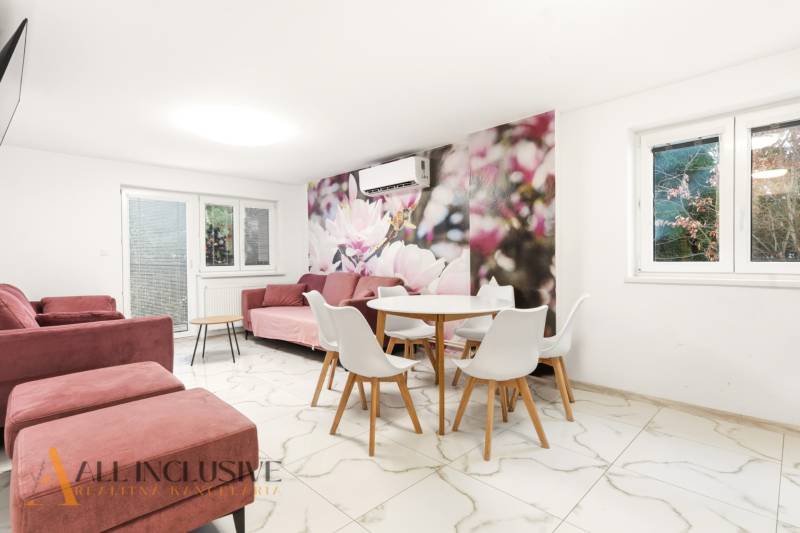 NADŠTANDARDNÁ REKREAČNÁ CHATA | DUCHONKA  - Obývacia miestnosť v Chate s kvetinovou tapetou, ružovými sedačkami a jedálenským stolíkom.