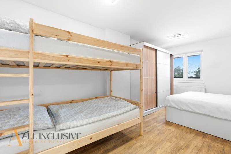 NADŠTANDARDNÁ REKREAČNÁ CHATA | DUCHONKA  - Interiér chaty s poschodovými posteľami, skriňou a podlahou s dreveným dekorom.