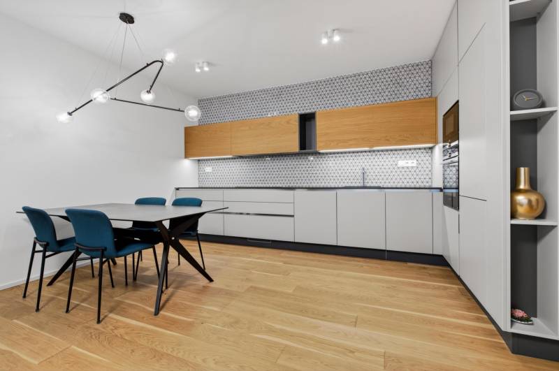 ︱ PREDAJ Nadštandardný 3-izb. byt v projekte Gansberg Koliba - Kuchyňa v 3-izbovom byte s jedálenským stolom, podlaha s dreveným dekorom.