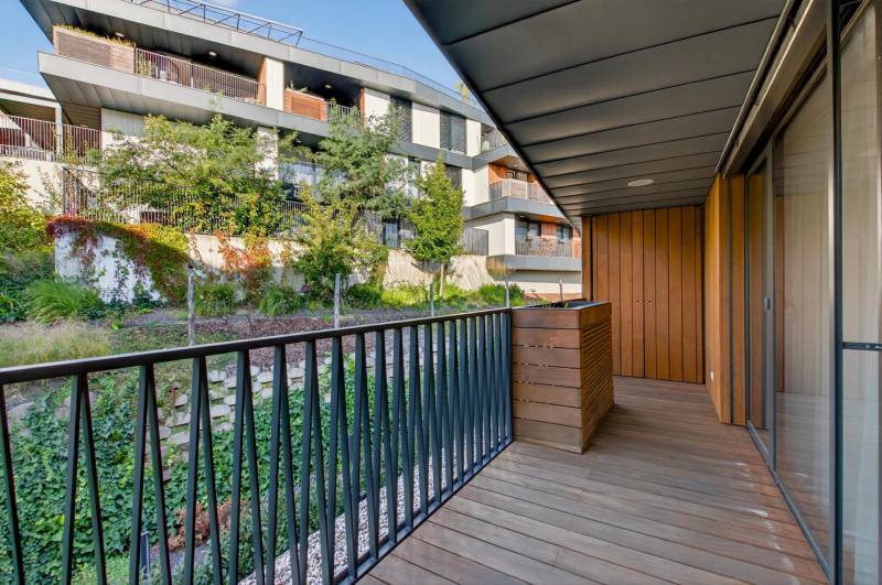 ︱ PREDAJ Nadštandardný 3-izb. byt v projekte Gansberg Koliba - Balkón 3-izbového bytu s výhľadom na zeleň, podlaha s dreveným dekorom.