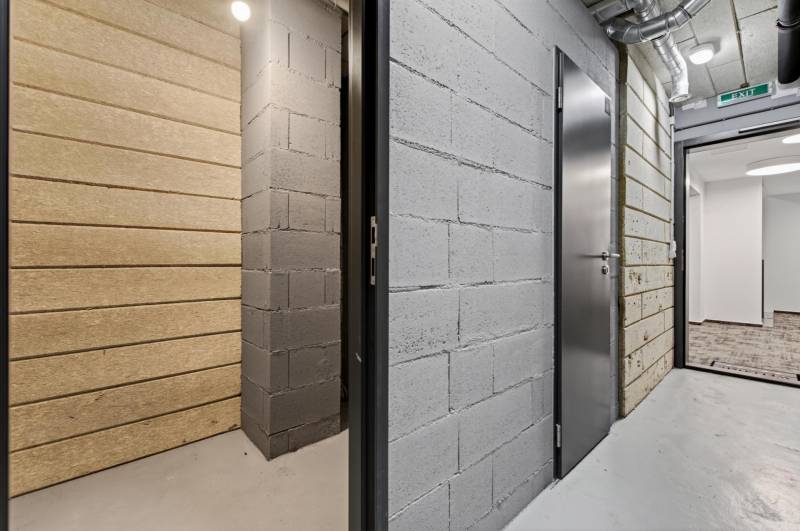 ︱ PREDAJ Nadštandardný 3-izb. byt v projekte Gansberg Koliba - Chodba so šedými a bielymi stenami, plechové dvere, miestnosť v pozadí.