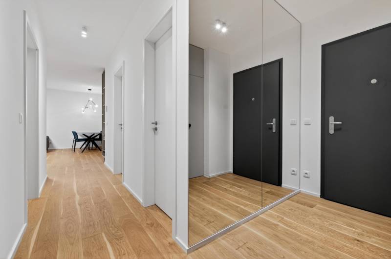 ︱ PREDAJ Nadštandardný 3-izb. byt v projekte Gansberg Koliba - Chodba s podlahou s dreveným dekorom a zrkadlom v 3-izbovom byte.