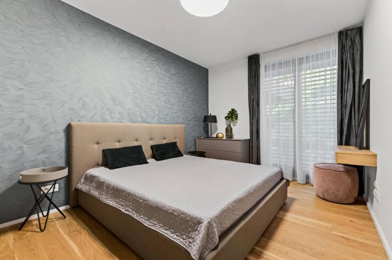 ︱ PREDAJ Nadštandardný 3-izb. byt v projekte Gansberg Koliba - Spálňa s dvojposteľou, tapetou a podlahou s dreveným dekorom v 3-izbovom byte.