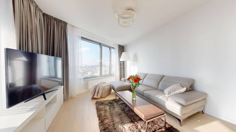 Elegantný byt na mieru s panorámou hradu  - Svetlá obývacia izba v 3-izbovom byte so sedačkou, stolíkom a televízorom.