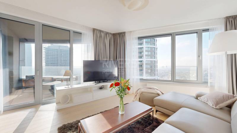 Elegantný byt na mieru s panorámou hradu  - Obývacia izba v 3-izbovom byte so sedačkou, televíziou a podlahou s dreveným dekorom.