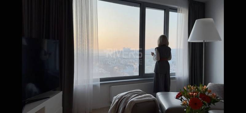 Elegantný byt na mieru s panorámou hradu  - Žena pozorujúca výhľad z 3-izbového bytu s kvetmi a podlahou s dreveným dekorom.