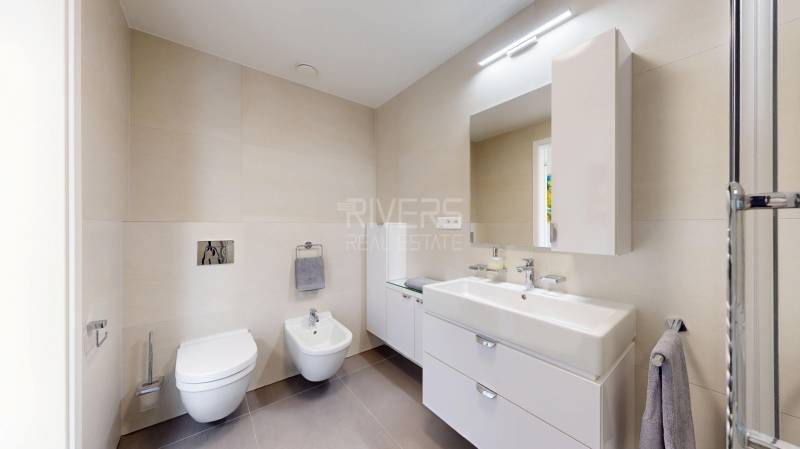 Elegantný byt na mieru s panorámou hradu  - Kúpeľňa v 3-izbovom byte s čistými líniami, svetlými obkladmi a dvojitým umývadlom.