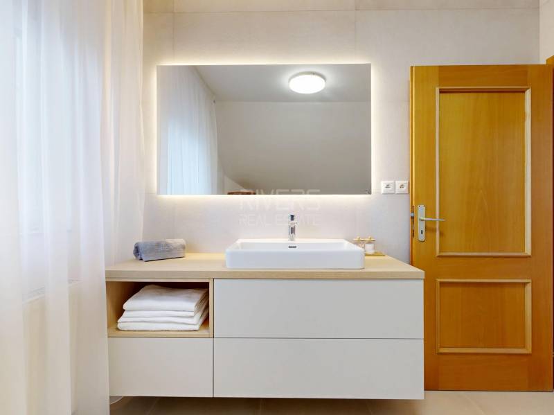 RIVERS - Veľkorysý rodinný dom po rekonštrukcii  - Kúpeľňa v rodinnom dome s umývadlom, zrkadlom a závesmi na drevenom dekore.