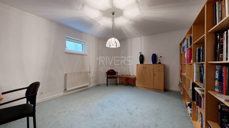 RIVERS - Veľkorysý rodinný dom po rekonštrukcii  - Izba v rodinnom dome s kobercovou podlahou, knihovníčkou a jednoduchým nábytkom.
