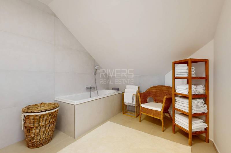 RIVERS - Veľkorysý rodinný dom po rekonštrukcii  - Kúpeľňa v rodinnom dome s vaňou, prúteným kreslom a poličkou s uterákmi.