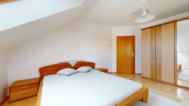 RIVERS - Veľkorysý rodinný dom po rekonštrukcii  - Spálňa v rodinnom dome s posteľou, vstavanou skriňou a podlahou s dreveným dekorom.