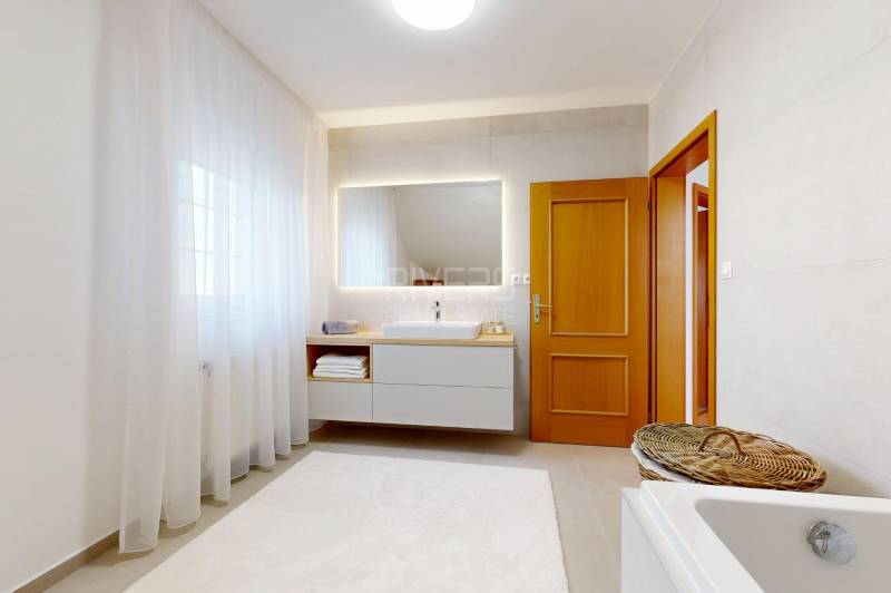 RIVERS - Veľkorysý rodinný dom po rekonštrukcii  - Kúpeľňa v rodinnom dome s umývadlom, vaňou, zrkadlom a bielym kobercom.