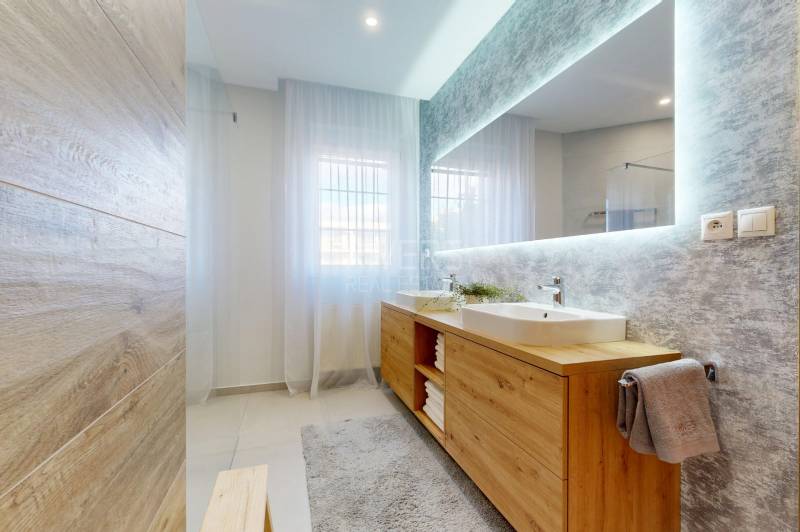 RIVERS - Veľkorysý rodinný dom po rekonštrukcii  - Kúpeľňa v rodinnom dome s veľkým zrkadlom, dvomi umývadlami a podlahou s dreveným dekorom.