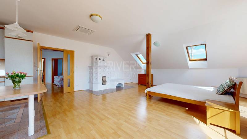 RIVERS - Veľkorysý rodinný dom po rekonštrukcii  - Podkrovná izba v rodinnom dome s kachľovou pecou a podlahou s dreveným dekorom.