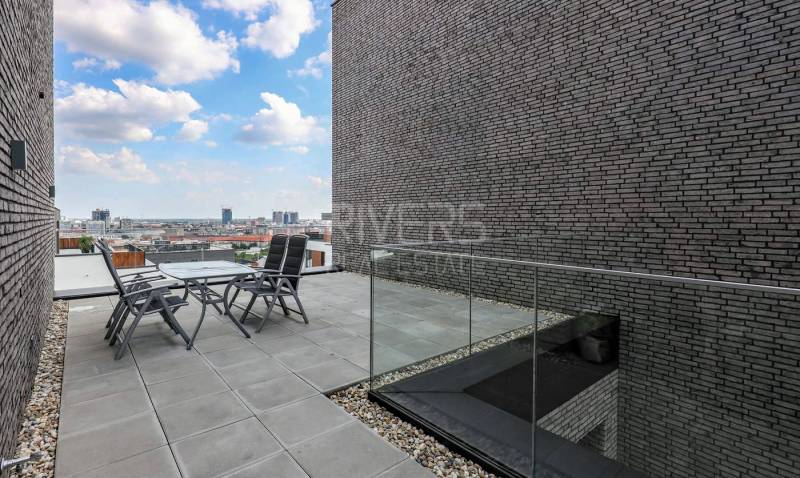 RIVERS I Prémiový 4-izbový byt s panoramatickým výhľadom na mesto - Terasa so stoličkami a stolom v 4-izbovom byte s výhľadom na Bratislavu.