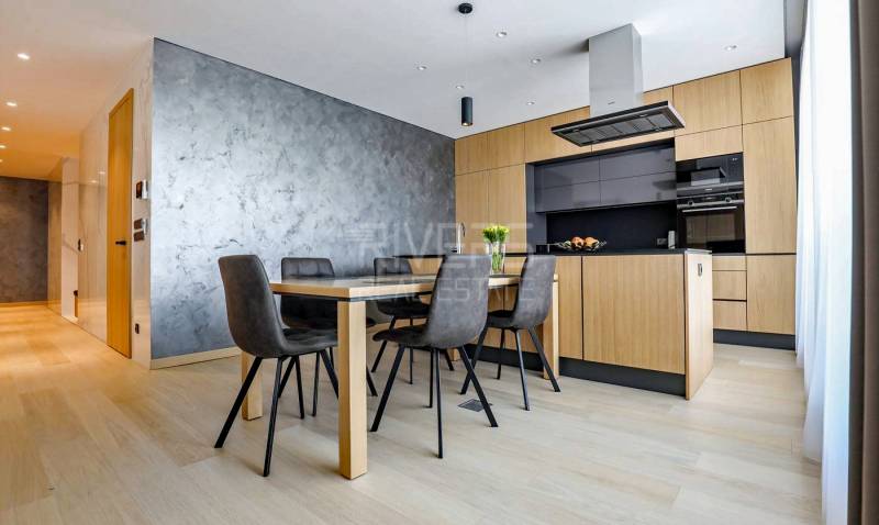 RIVERS I Prémiový 4-izbový byt s panoramatickým výhľadom na mesto - Kuchyňa v 4-izbovom byte s podlahou s dreveným dekorom a jedálenským stolom.