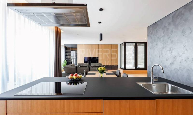 RIVERS I Prémiový 4-izbový byt s panoramatickým výhľadom na mesto - Kuchyňa v 4-izbovom byte so sklenenou stenou a jedálenským stolom s kvetmi.