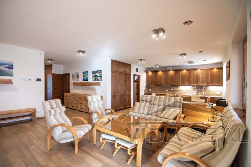 Nadštandardný 4-izbový rodinný dom s garážou a veľkým pozemkom - Interiér rodinného domu s priestrannou obývačkou, kuchynskou linkou a podlahou s dreveným dekorom.