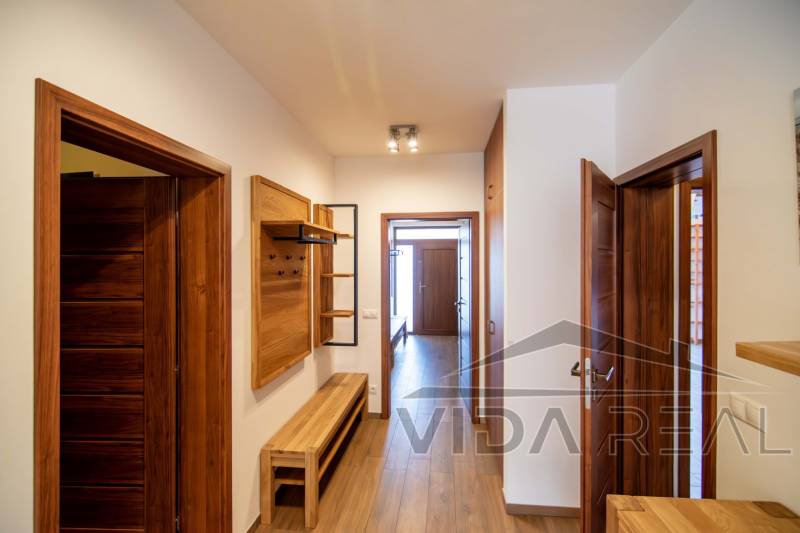 Nadštandardný 4-izbový rodinný dom s garážou a veľkým pozemkom - Chodba v rodinnom dome s dreveným dekorom na podlahe a nábytku.