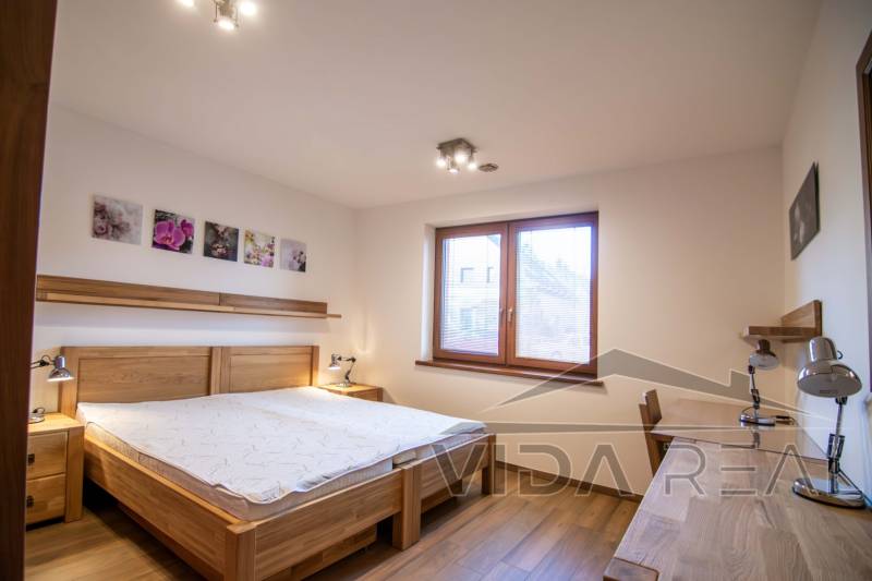 Nadštandardný 4-izbový rodinný dom s garážou a veľkým pozemkom - Spálňa v rodinnom dome s posteľou, nočnými lampami a podlahou s dreveným dekorom.