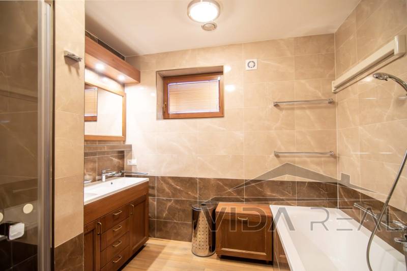 Nadštandardný 4-izbový rodinný dom s garážou a veľkým pozemkom - Kúpeľňa v rodinnom dome s vaňou, umývadlom, sprchovým kútom a podlahou s dreveným dekorom.