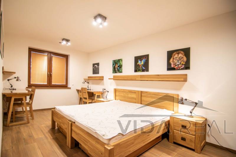 Nadštandardný 4-izbový rodinný dom s garážou a veľkým pozemkom - Spálňa v rodinnom dome s podlahou s dreveným dekorom, obrazmi a pracovnými stolmi.