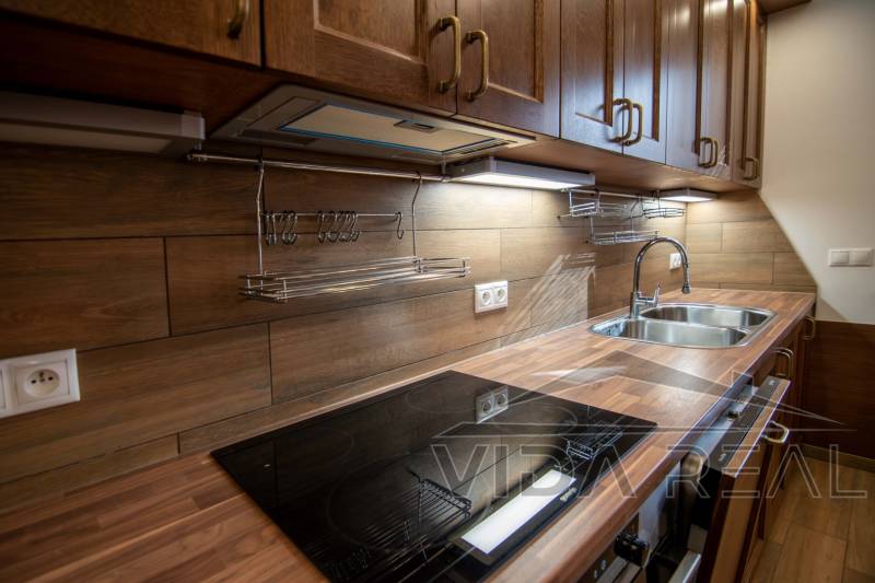 Nadštandardný 4-izbový rodinný dom s garážou a veľkým pozemkom - Kuchyňa v rodinnom dome s podlahou s dreveným dekorom a kuchynskou linkou z dreva.