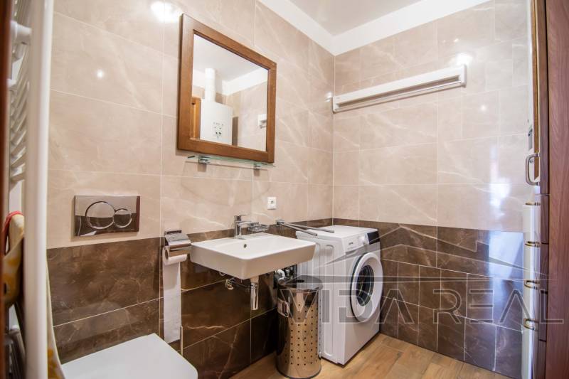 Nadštandardný 4-izbový rodinný dom s garážou a veľkým pozemkom - Kúpeľňa v rodinnom dome s práčkou, umývadlom a podlahou s dreveným dekorom.