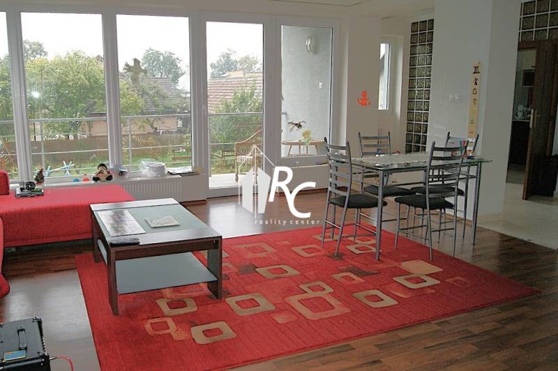 Zrekonštruovaný rodinný dom s peknou záhradou, Bystrička - Obývacia izba v rodinnom dome s podlahou s dreveným dekorom a červeným kobercom.