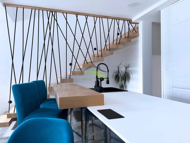 Poschodový rodinný dom v Michalovciach  - Interiér rodinného domu so schodiskom, modrými stoličkami a kuchynským pultom.