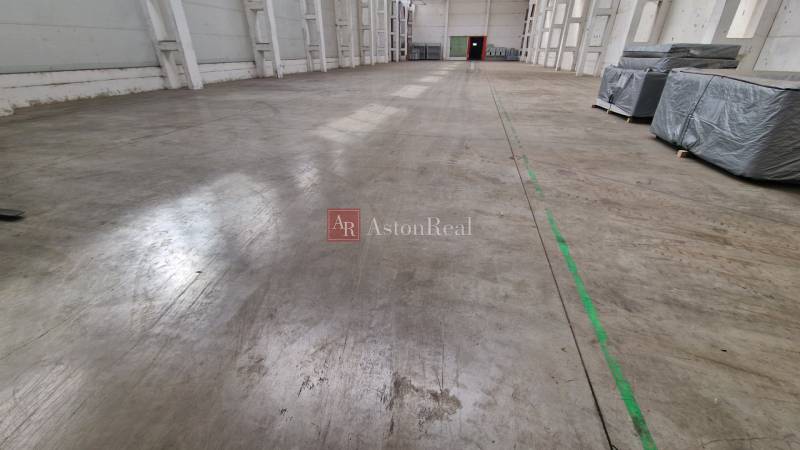 Prenájom HALA - SKLADOVÉ PRIESTORY - POPRAD od 2500 m2 - 5000 m2 - Priestranný interiér Skladov a hál s betónovou podlahou a balíkmi na ľavej strane.