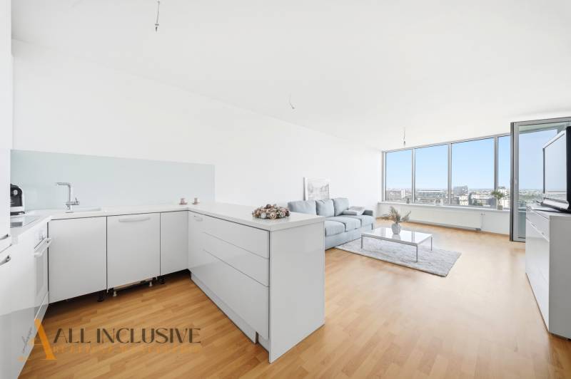 Na predaj luxusný 2-izb. byt s loggiou v Bratislave  - Svetlá kuchyňa s obývacou izbou, podlaha s dreveným dekorom, pohovka, veľké okná.