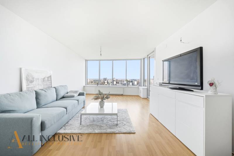 Na predaj luxusný 2-izb. byt s loggiou v Bratislave  - Obývacia izba v 2-izbovom byte s pohovkou, televíziou a podlahou s dreveným dekorom.