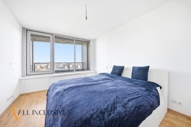 Na predaj luxusný 2-izb. byt s loggiou v Bratislave  - Spálňa v 2-izbovom byte s posteľou a veľkým oknom, podlaha s dreveným dekorom.