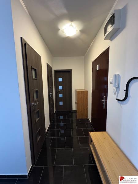 Prenájom 2-izb bytu v Bratislave-Rača - Chodba so vstupnými dverami v 2-izbovom byte, s tmavou podlahou a drevenými prvkami.