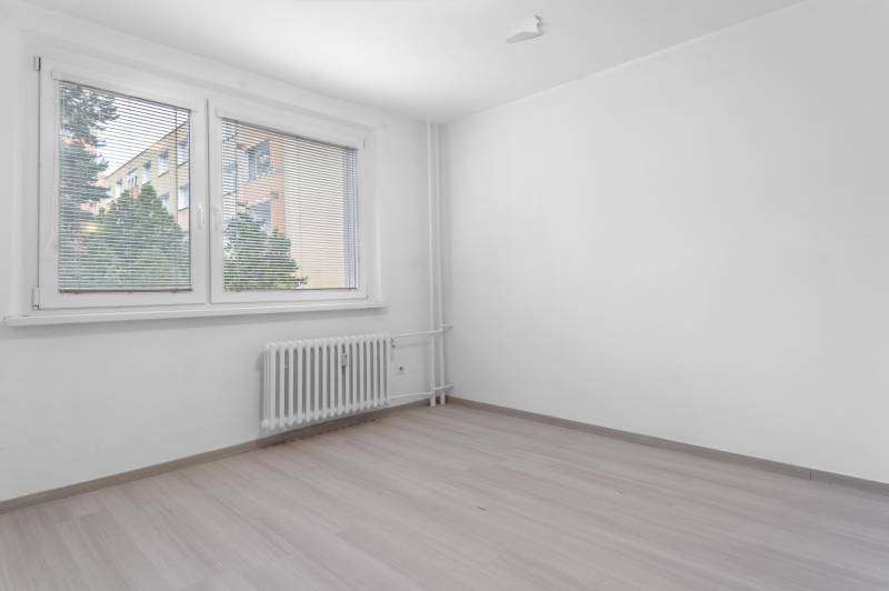 I Predaj 3- izbového bytu v Dúbravke - Prázdna izba s podlahou s dreveným dekorom a oknom v 3-izbovom byte.