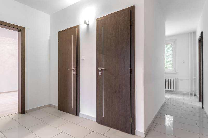 I Predaj 3- izbového bytu v Dúbravke - Interiér 3-izbového bytu s dlaždicovou podlahou a bielymi stenami, tmavé dvere.