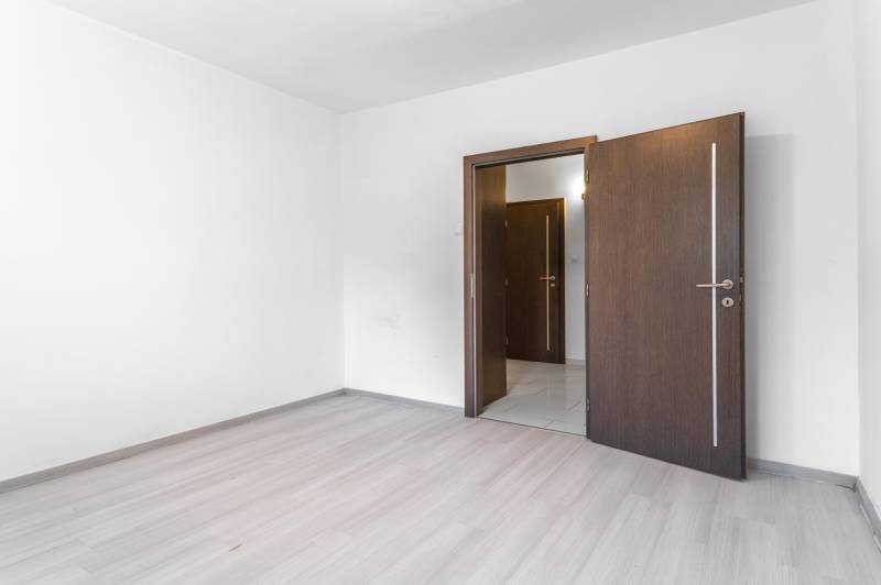 I Predaj 3- izbového bytu v Dúbravke - Izba s podlahou s dreveným dekorom a otvorenými dverami v 3-izbovom byte.