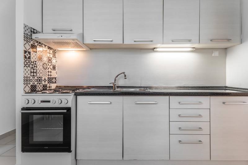 I Predaj 3- izbového bytu v Dúbravke - Kuchynská linka v 3-izbovom byte s keramickým obkladom a bielou rúrou.