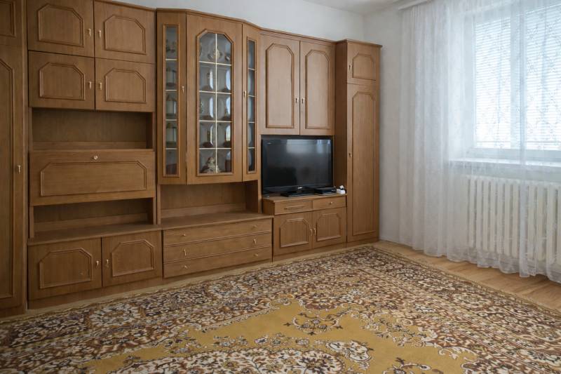 Bývajte vo svojom : dom a  pozemok 690 m², Veľké Ripňany 77.000,-EUR - Obývacia izba v rodinnom dome s drevenou obývacou stenou a vzorovaným kobercom.