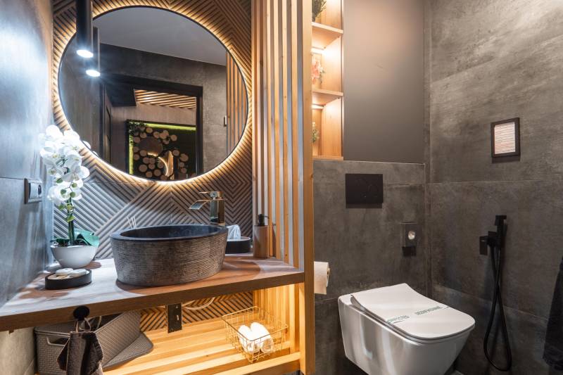 | Luxusný dvojúrovňový mezonet v Starom Meste - Kúpeľňa v 3-izbovom byte s okrúhlym zrkadlom, rustikálnym umývadlom a dekoratívnym osvetlením.