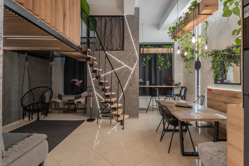 | Luxusný dvojúrovňový mezonet v Starom Meste - Podlaha s dreveným dekorom, schody, zelené rastliny a interiér 3-izbového bytu.