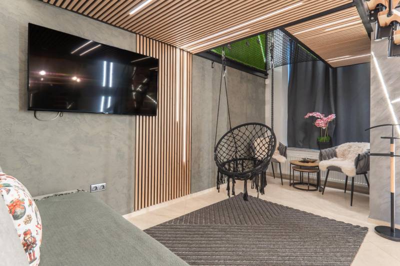 | Luxusný dvojúrovňový mezonet v Starom Meste - Obývačka v 3-izbovom byte so zavesenou stoličkou, TV a dekoratívnym obkladom.