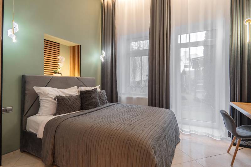 | Luxusný dvojúrovňový mezonet v Starom Meste - Spálňa v 3-izbovom byte s veľkým oknom, závesmi a pohodlnou posteľou.