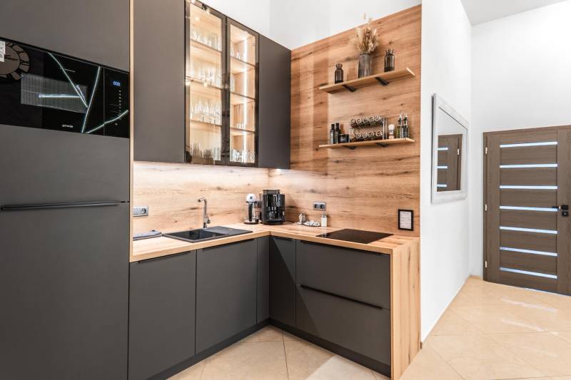 | Luxusný dvojúrovňový mezonet v Starom Meste - Kuchyňa v 3-izbovom byte s podlahou s dreveným dekorom a tmavými skrinkami.