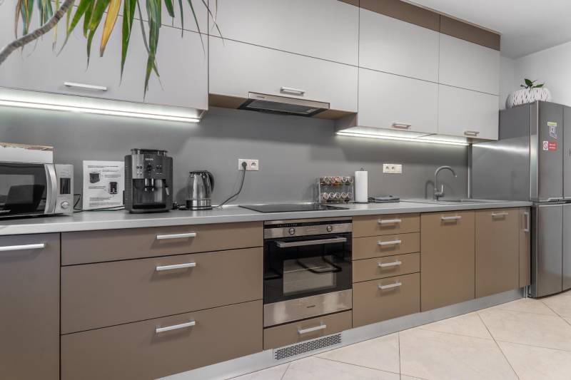 I Luxusný byt v historickom centre Bratislavy - Kuchyňa v 2-izbovom byte, moderné spotrebiče, šedá pracovná doska a úložné skrinky.